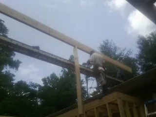 Carpenter setting a ridge beam over a new addition frame — Ice Dam Removal by Roofing Brothers in Walthall
