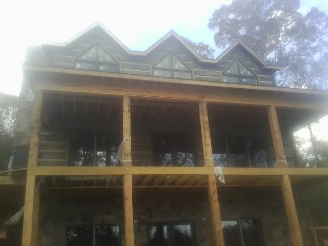 Dormers and porch framing on a large log home under construction — Roof Coating work by our crew in Walthall
