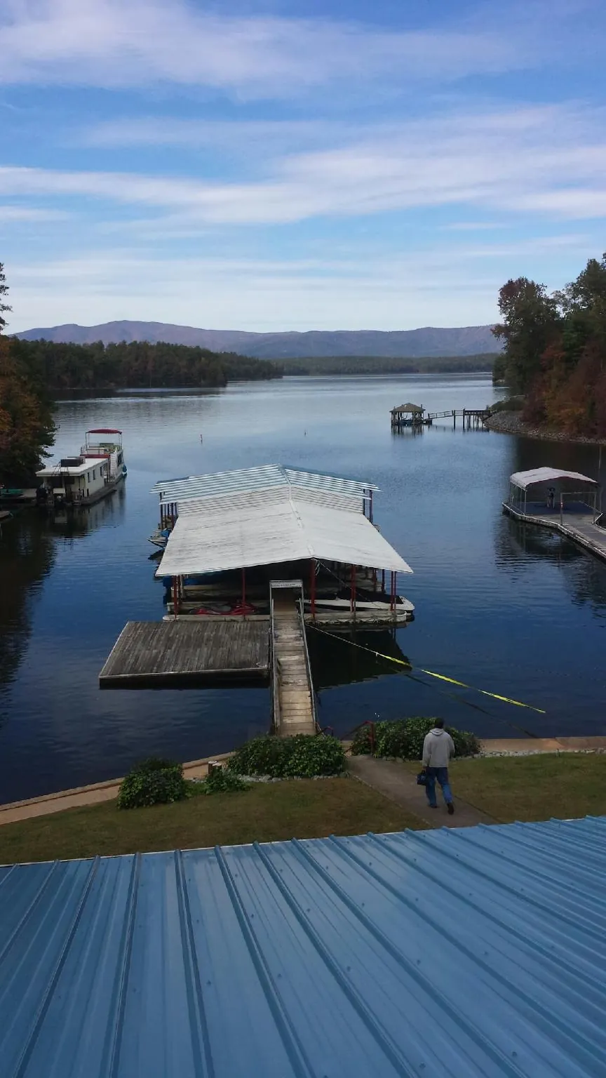 View across a lake from a newly installed blue metal roof in Walthall