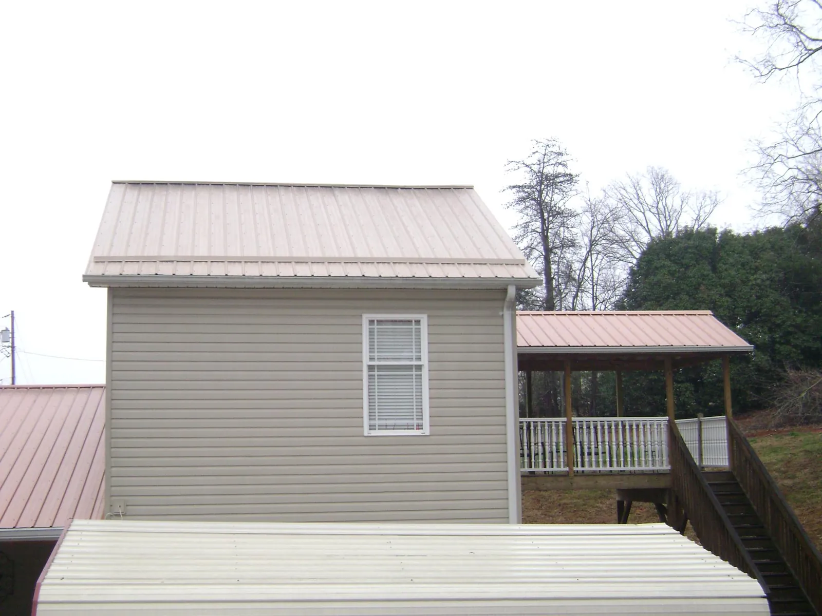 Tan metal roofs on a two story addition and attached porch, from a Roof Replacement job in Walthall