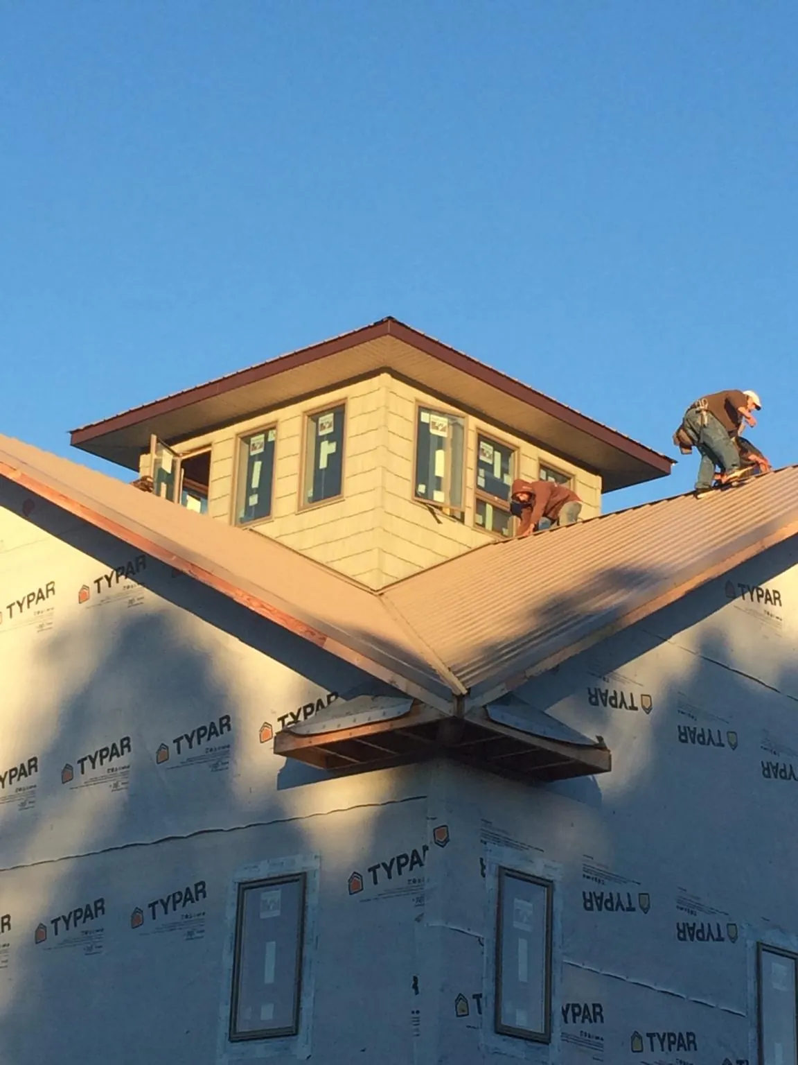 Roofers working around a rooftop cupola on a new metal roof at sunset — Roof Waterproofing in Walthall by Roofing Brothers